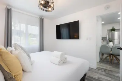 a bedroom with a white bed with a tv on the wall at 3 Bed House with Fire Pit Table and BBQ - Downtown in San Diego