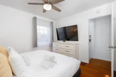 a white bedroom with a white bed and a flat screen tv at 2 Bedroom - Ocean View Hot Tub Parking - 8 Guest in San Diego