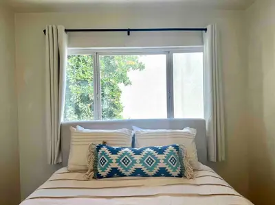 a bed in front of a window with pillows at Minimalist 1 bed by Airport & Old Town in San Diego