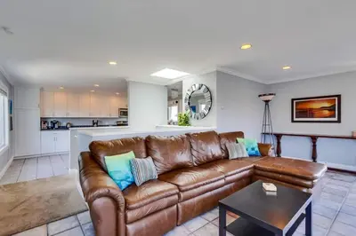 a living room with a brown leather couch and a kitchen at Mission Beach Townhome Getaway in San Diego