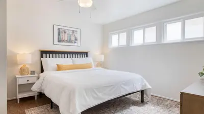 a white bedroom with a large bed and windows at Surfrider I by AvantStay Walk to the Beach Patio in Newport Beach