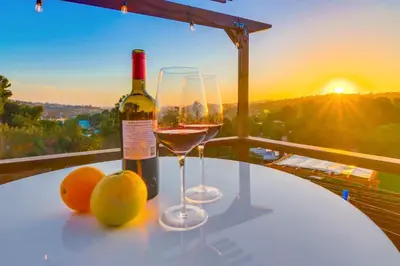 a bottle of wine and two glasses on a table with the sunset at The Helix House - Pool & Mountain Views in La Mesa