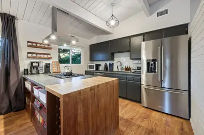 a kitchen with a stainless steel refrigerator and wooden floors at Agua Dulce - Mid Century Oasis - Pool &Hot Tub in Spring Valley
