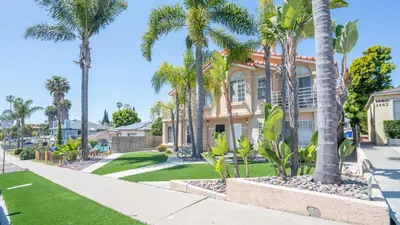 a house with palm trees and a sidewalk at The Oliver - Pacific Beach Hideaway in San Diego