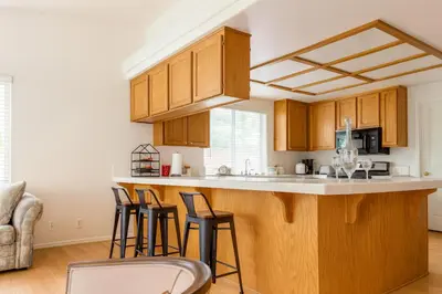 a kitchen with wooden cabinets and bar stools at Western Horizon Home in Hemet
