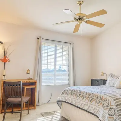 a bedroom with a bed and a desk and a ceiling fan at Western Horizon Home in Hemet