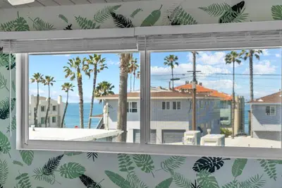 a window with a view of the ocean and palm trees at Day in Paradise at Oside Palms in Oceanside