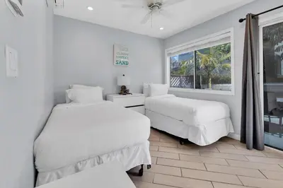 two beds in a white room with a window at Stunning Beach Haven! Steps to the Beach & Pet Friendly! in San Diego
