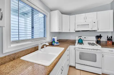 a kitchen with white cabinets and a sink and a window at Stunning Beach Haven! Steps to the Beach & Pet Friendly! in San Diego