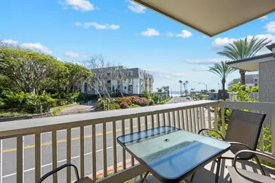 a table and chairs on a balcony with a view of a street at B2 - Whispering Waves in Oceanside