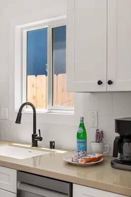 a kitchen counter with a sink and a plate of food at Modern and Cozy in PB with Patio and Firepit in San Diego
