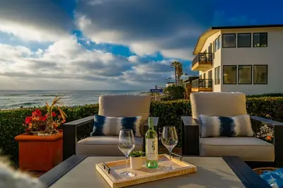 a patio with two chairs and a table with wine glasses at Oceanfront Townhome with Breathtaking Views in San Diego