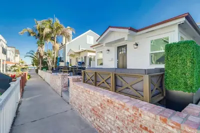 a white house with a gate and a fence at Breezy Bayside Cottage in San Diego