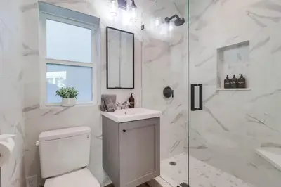 a white bathroom with a toilet and a shower at Breezy Bayside Cottage in San Diego