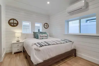 a white bedroom with a bed and a window at Breezy Bayside Cottage in San Diego