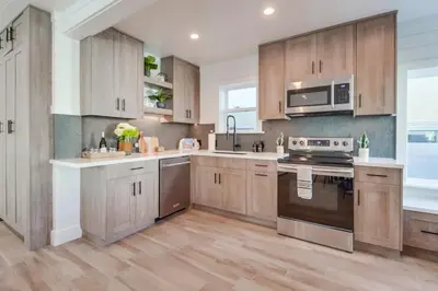 a kitchen with wooden cabinets and stainless steel appliances at Breezy Bayside Cottage in San Diego