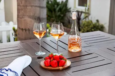 two glasses of wine and strawberries on a wooden table at Prime Mission Beach Getaway in San Diego