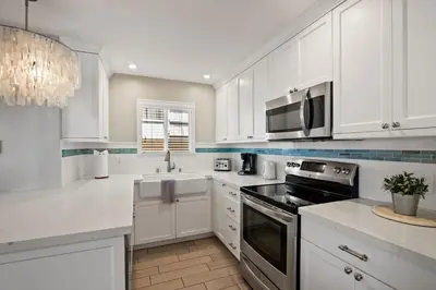 a white kitchen with white cabinets and a microwave at Coastal Chic at Windansea in San Diego