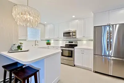 a kitchen with white cabinets and a stainless steel refrigerator at Coastal Chic at Windansea in San Diego