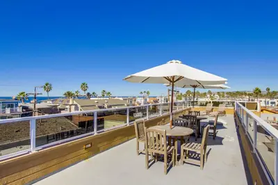 a patio with tables and chairs and an umbrella at Massive Beach Home with Ocean View & Amazing Rooftop in San Diego