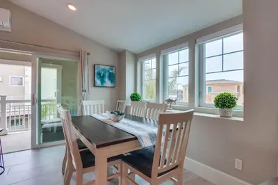 a dining room with a table and chairs and windows at Newly Built Bayside Dream, Fire Pit & Bay Views in San Diego