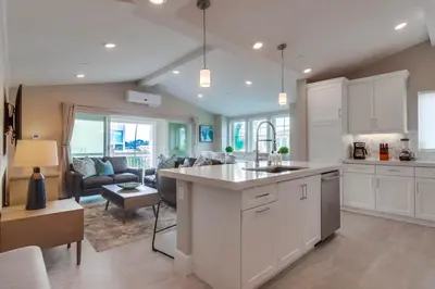 a kitchen with white cabinets and a living room at Newly Built Bayside Dream, Fire Pit & Bay Views in San Diego