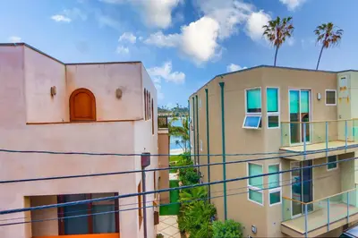 two buildings with palm trees in the background at Newly Built Bayside Dream, Fire Pit & Bay Views in San Diego