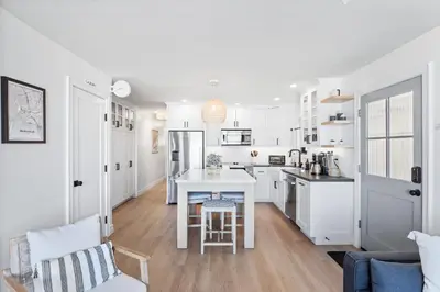 a kitchen with white cabinets and a table in a room at Luxury Ground S Oceanfront Unit with Boardwalk Lounge Firepit - AC in San Diego