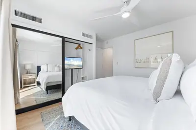 a white bedroom with a large bed and a mirror at N Oceanfront Masterpiece with Rooftop & Hot Tub in San Diego