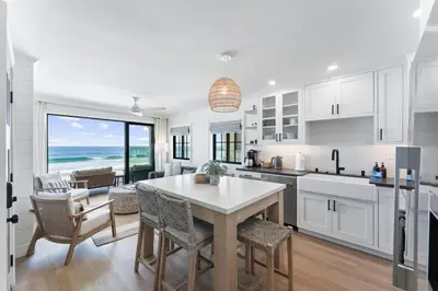 a kitchen with white cabinets and a table with chairs at N Oceanfront Masterpiece with Rooftop & Hot Tub in San Diego