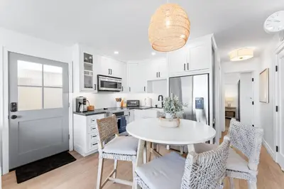 a kitchen with white cabinets and a table and chairs at Entire Ground Beachfront Luxury Unit with Patio in San Diego