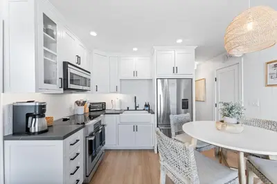 a kitchen with white cabinets and a table with chairs at Entire Ground Beachfront Luxury Unit with Patio in San Diego