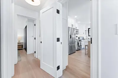 a hallway with white walls and a kitchen with a refrigerator at Entire Ground Beachfront Luxury Unit with Patio in San Diego