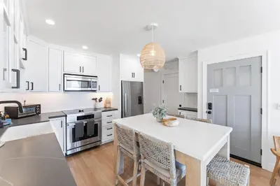 a kitchen with white cabinets and a table with chairs at Luxury oceanfront fourplex with roof deck sleeps 22 in San Diego