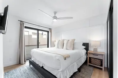 a white bedroom with a large bed and a window at Luxury oceanfront fourplex with roof deck sleeps 22 in San Diego