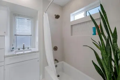 a white bathroom with a bath tub and a plant at The Shining Sea A in Oceanside