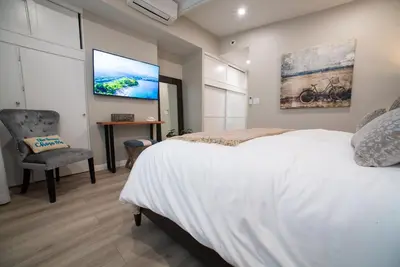 a bedroom with a white bed and a flat screen tv at La Jolla Windansea Luxury Apt in San Diego