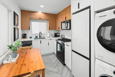 a kitchen with white cabinets and a wooden table at Modern 1 BR Apt - Walk to Ocean & Cafes in San Diego