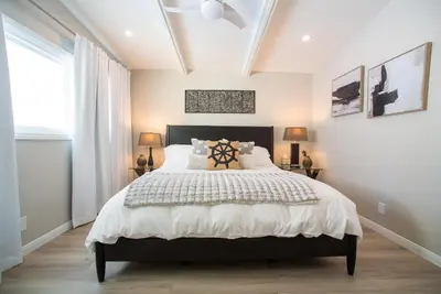 a bedroom with a large bed with a black headboard at La Jolla Windansea Luxury Cottage in San Diego