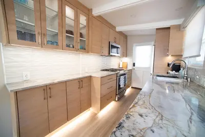 a kitchen with wooden cabinets and a marble floor at La Jolla Windansea Luxury Cottage in San Diego