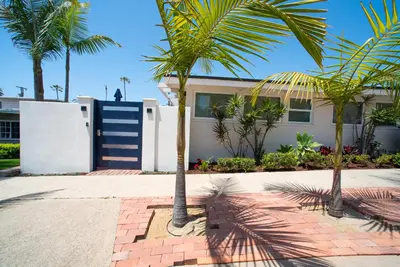 a house with palm trees in front of it at La Jolla Windansea Luxury Cottage in San Diego
