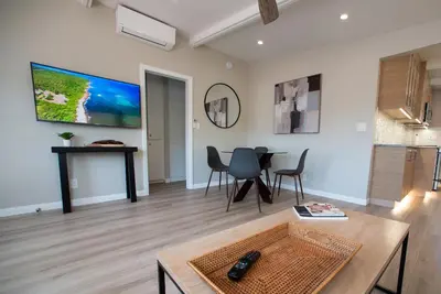 a living room with a table and a tv on the wall at La Jolla Windansea Luxury Cottage in San Diego