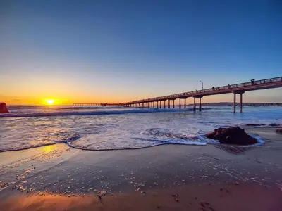 a pier on the beach at sunset with the ocean at Modern 1 BR Beach Waves and Sunshine in San Diego