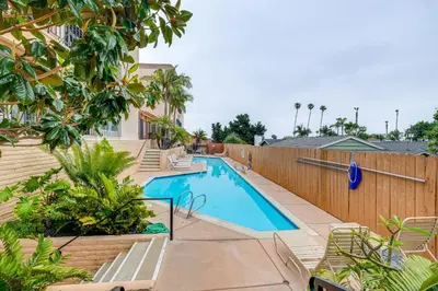a swimming pool with benches next to a wooden fence at Condo Near Hospitals and half Mi to Mission Bay! in San Diego