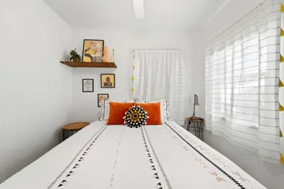 a bedroom with a large white bed with orange pillows at North Park Boho Bungalow by Rather Be Properties in San Diego