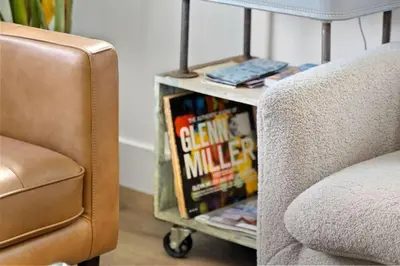 a book cart with books on it next to a couch at North Park Boho Bungalow by Rather Be Properties in San Diego