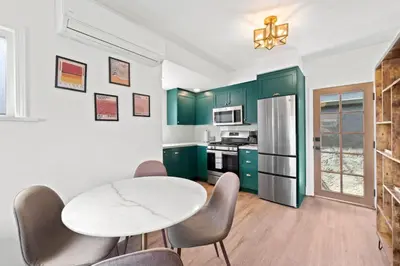 a kitchen with green cabinets and a table and chairs at North Park Boho Bungalow by Rather Be Properties in San Diego