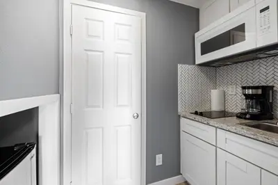a kitchen with white cabinets and a white door at 1628 West Oceanfront Oasis - All Units in Newport Beach