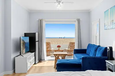 a living room with a blue couch and a tv at 1628 West Oceanfront Oasis - All Units in Newport Beach