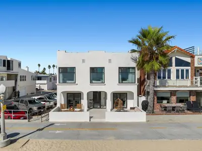 a white building with a palm tree in front of it at 1628 West Oceanfront Oasis 1,2,3 in Newport Beach